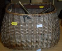 A fly fisherman's wicker creel with fish hole lid containing a quantity of fishing tackle to