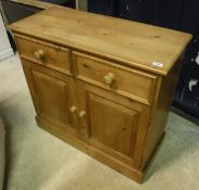 A pine cupboard with two short drawers over two cupboard doors to plinth base
