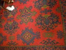 A Turkish rug, the central panel set with repeating motifs on a red ground within a stepped red,