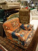 An armchair with orange ground and geometric patterned tapestry upholstery on turned and castored