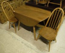 A blond Ercol drop-leaf dining table on stick legs together with four blond Ercol stickback kitchen