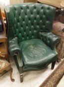 A green leather wingback type chair with button back on square tapering legs