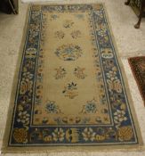 A Chinese rug, the central panel set with floral sprays on a fawn ground, within a pink,
