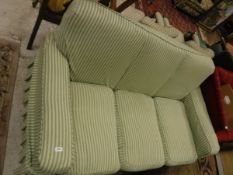 A three seater sofa with green upholstery and cream and green striped cover