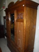 An Edwardian walnut wardrobe with central mirrored panel flanked by two doors over five drawers