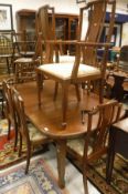 An Edwardian mahogany extending dining table with square tapering legs to spade feet together with