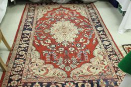 A Persian rug, the central panel set with floral decorated medallion on a red ground,