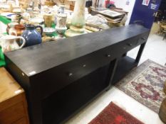 A modern ebonised oak dresser with plain top over four drawers on square supports united by a pot