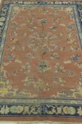 A Chinese carpet, the central panel set with floral sprays on a pink ground, within a stepped pink,