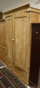 A pine two door wardrobe with single large drawer raised on plinth base