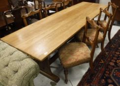 An oak refectory table together with a set of six bar back dining chairs with carved top rails and