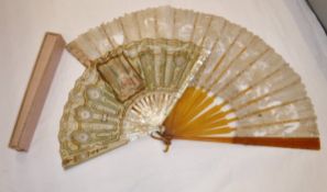 A 19th century mother of pearl stick fan with printed decoration depicting a lady in a boudoir
