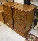 A pair of walnut bedside chests of three drawers and brushing drawer raised on plinth base