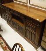 A walnut sideboard with three drawers above four cupboards with fielded panel doors with carved