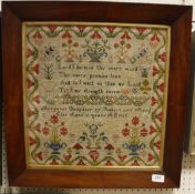 A 19th Century sampler depicting a religious verse within a flower-decorated border named and dated