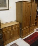 A pine wardrobe, the cupboard section above two drawers and plinth base,