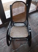 An early 20th Century ebonised bentwood rocking chair with caned back and seat in the manner of