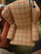 A wingback armchair with orange and red check upholstery on mushroom coloured ground together with