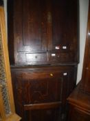An early 19th Century oak hanging corner cupboard of two doors over two drawers,