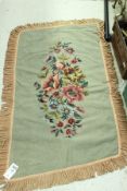 A needlework rug, the central panel set with floral spray on a plain sage green ground,