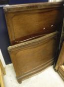 A pair of Edwardian mahogany single bedsteads with serpentine footboards and carved decoration