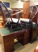 A mahogany kneehole desk and two Ercol elbow chairs