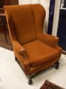 An early 20th Century wing back arm chair in the 19th Century manner and orange upholstery