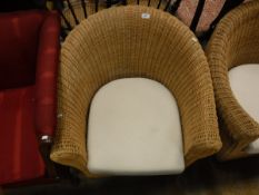 A pair of wicker tub chairs with cream ground cushions