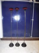 A set of three 19th Century wig stands with the velvet covered tops raised on brass poles to glazed