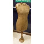 A vintage tailor's dummy with canvas-covered body raised on a wooden telescopic ringed support and
