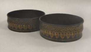 A pair of 19th Century ebonised and gilt decorated papier mache wine coasters with Greek key and