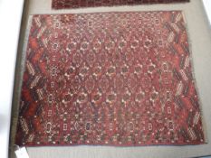 A Tekke Turkamen rug, the central panel set with elephant foot style medallions on a dark ground,