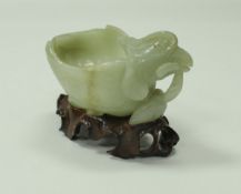 A Chinese mutton fat jade figure of an exotic bird as a bowl on a carved wooden stand, 11.