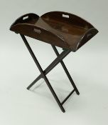 A 19th Century mahogany butler's tray of oval drop sided form, raised on a folding stand,