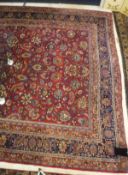 A Mashad carpet, the central panel set with all over floral decoration on a plum ground,