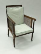 A circa 1900 mahogany framed and caned Bergere library chair with slender turned and reeded