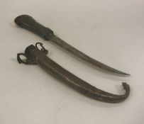 A 19th Century Indian dagger with horn handle and slightly curved blade in an embossed copper