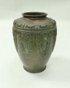 A Chinese patinated bronze vase of urn form decorated in relief with stylised grotesque masks,