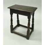 A 17th Century oak joint stool the plain top raised on ringed and turned supports to block feet