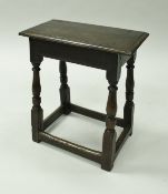 A 17th Century oak joint stool the plain top raised on ringed and turned supports to block feet