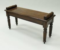 A mahogany window seat in the Victorian manner with tapered reeded legs,