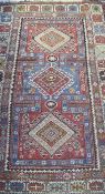 A Shirvan rug, the central panel set with three repeating medallions on a red and blue ground,