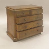 A Victorian burr walnut veneered miniature chest of two short over three long drawers on a plinth