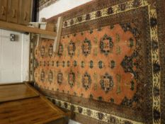 An Afghan rug, the central panel set with repeating medallions on a rust ground,
