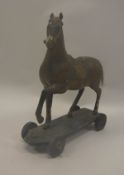 A 19th Century papier mache horse figure with saddle on wheels 31 cm long