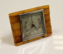 A 1920's Baltic amber mounted travel clock, the dial set with Arabic numerals in a chromed frame,