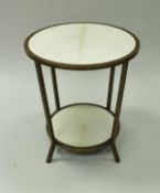 A circular brass framed velum covered two tier occasional table in the Art Deco taste,