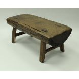 An Indonesian pig bench of half cut trunk form, raised on splayed supports,