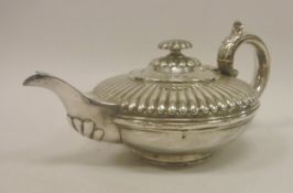 A William IV silver teapot of compressed circular form with half reeded body and knop cover (by