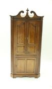 A George II walnut free-standing corner cupboard with swan neck pediment and a carved centre finial